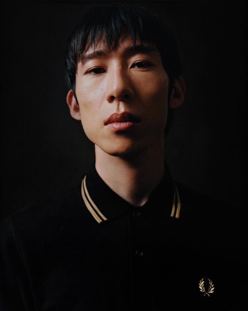 Portret van een man in een zwarte Fred Perry-polo met contrastbies aan de kraag